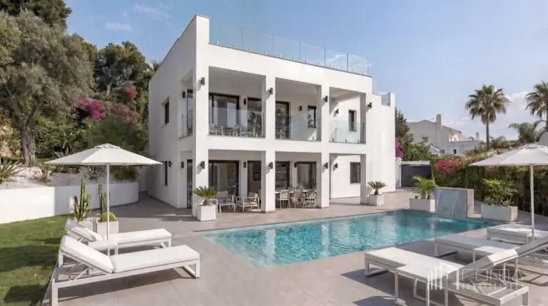 Modern white villa facade, landscaped garden, and private swimming pool with sun loungers, masterfully delivered by roma arquitectura studio, luxury puerto banus architects and interior designers for turnkey renovations