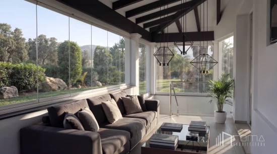 Architects in malaga developing exclusive luxury villas 8 La quinta hills sunroom after renovation: dark contemporary sofa, geometric pendant lights and full‑height glazing with floor‑to‑ceiling windows overlooking the garden — by roma arquitectura studio, luxury architects and interior designers in benahavis.